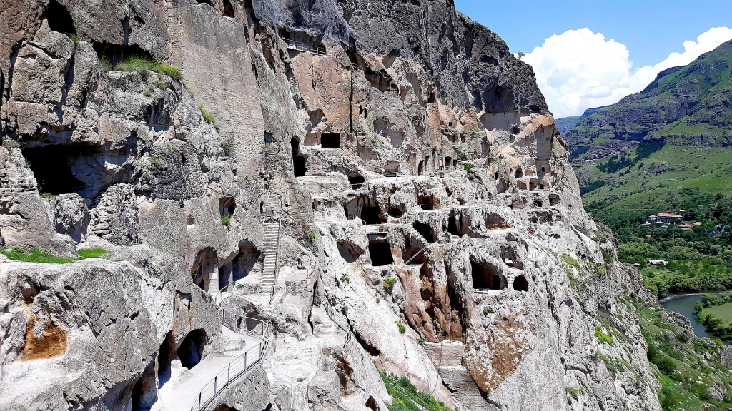 Panoramic view of Vardzia's honeycombed cave dwellings overlooking the green river valley.