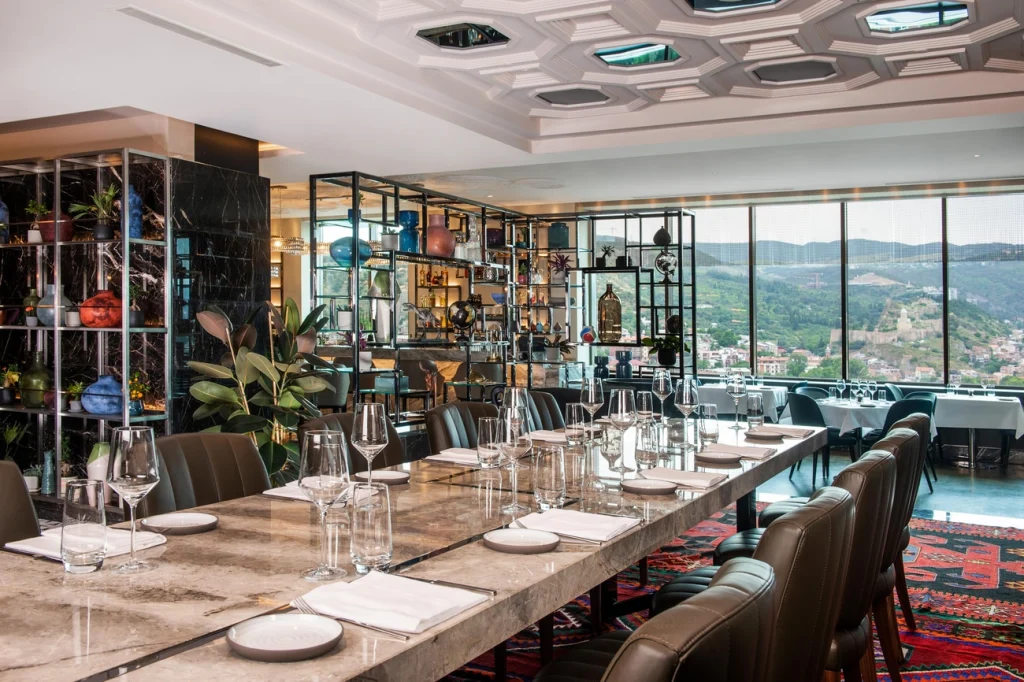 ATI Rooftop Restaurant — Elegant rooftop restaurant dining room with long table setting and panoramic valley view.