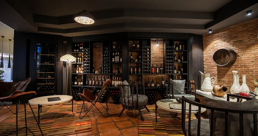 Adamo — Cozy wine lounge with shelves of bottles, leather chairs, and warm lighting.