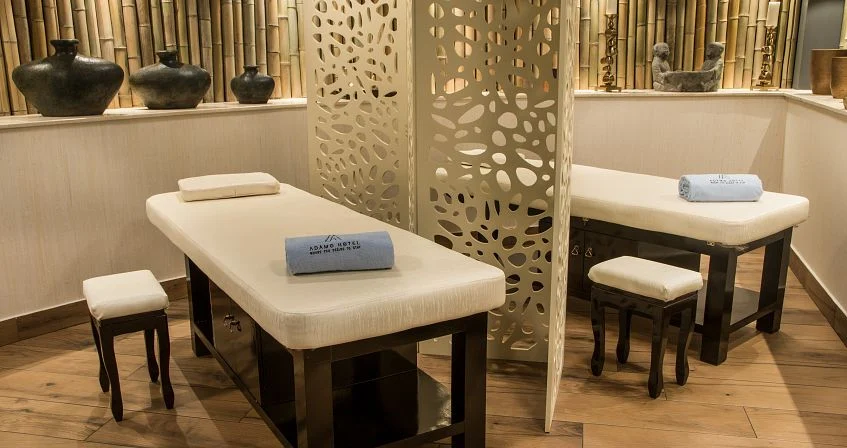 Adamo — Spa treatment room with two massage beds separated by a decorative partition.