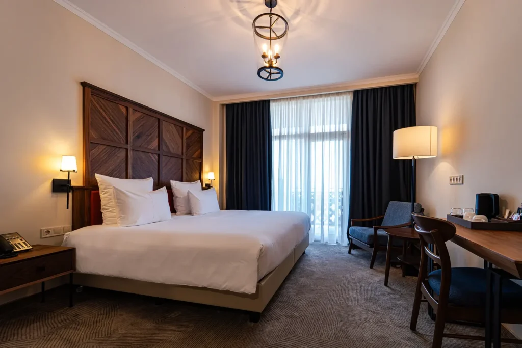 Agarani Estate — Spacious hotel room with king bed, wooden headboard, and seating area.