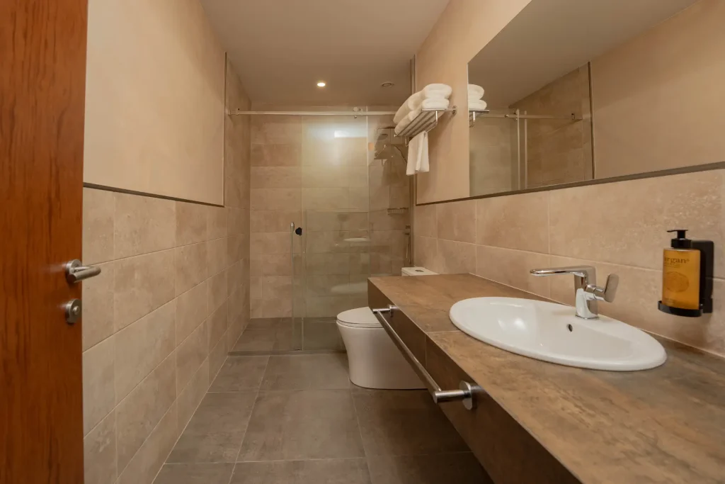 Agarani Estate — Modern bathroom with glass shower, wooden countertop, and single sink.
