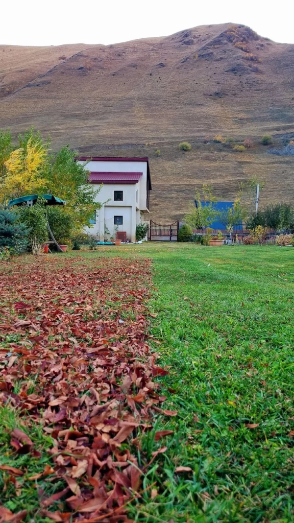 Allegria House Kazbegi — House exterior with mountain backdrop and autumn garden view.