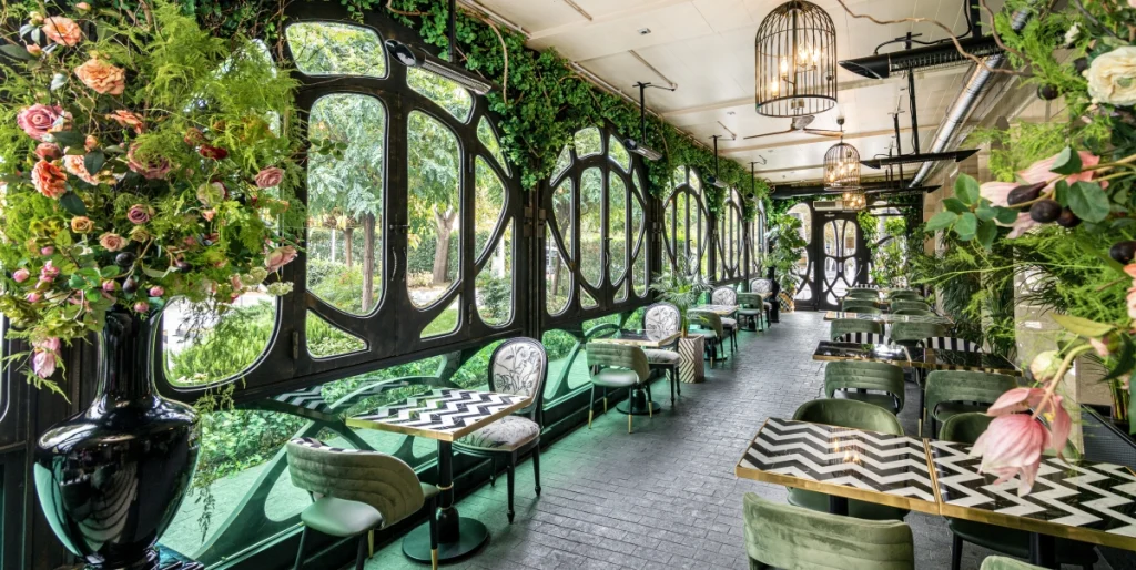Ambassadori Tbilisi — Glass-walled restaurant terrace decorated with lush greenery and flowers.