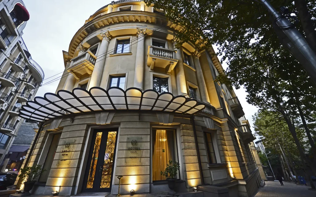 Astoria Tbilisi — Illuminated corner facade of the historic Astoria Tbilisi building at dusk.
