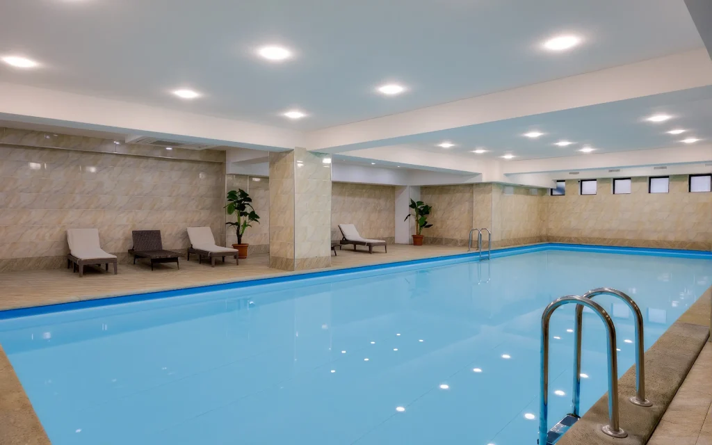 Astoria Tbilisi — Indoor swimming pool with loungers and warm tiled surroundings.