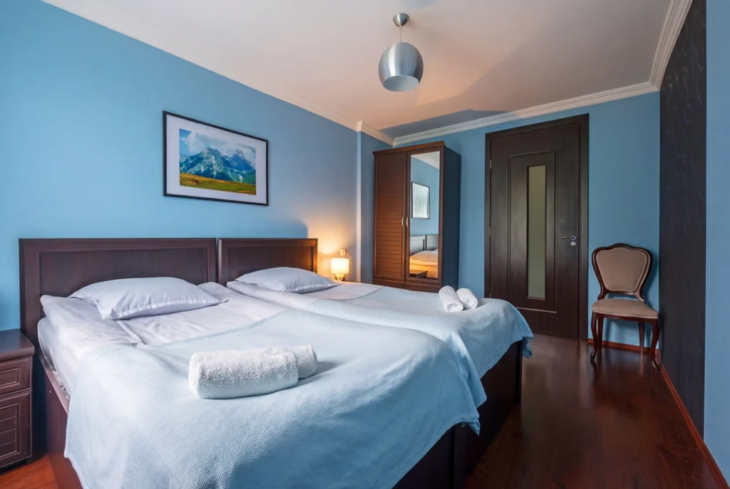 Becho House — Twin bed guest room with blue walls and dark wood furnishings.