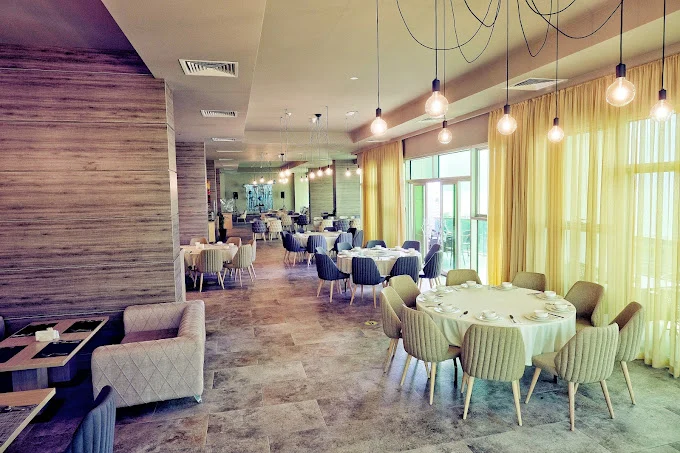 Best Western Premier Batumi — Bright hotel restaurant with round tables, pendant lights, and large windows.