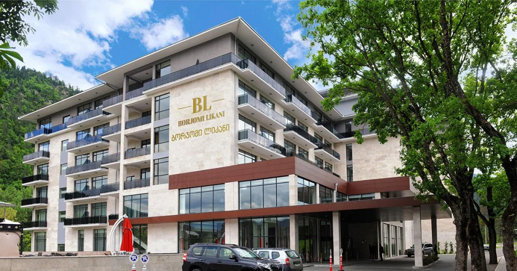 Borjomi Likani — Modern multi-story hotel building surrounded by trees and green lawn.