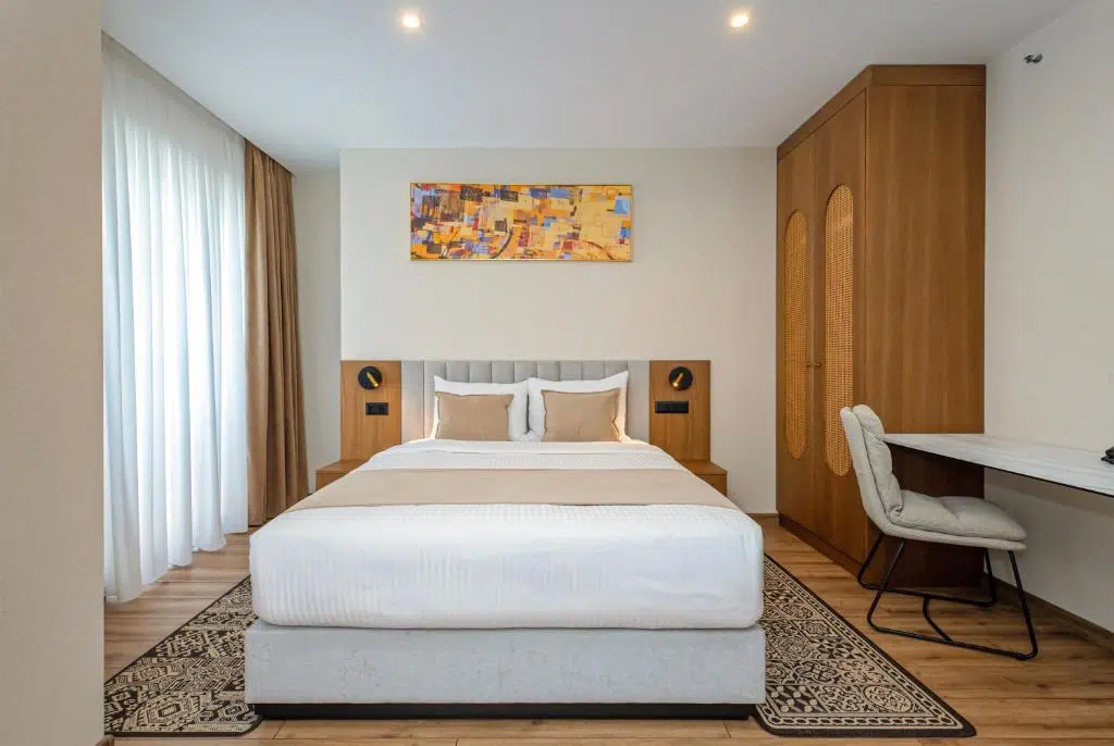 Boutique Hotel Calligraphy Tbilisi — Modern hotel bedroom with king bed, wooden wardrobe, and desk with chair.