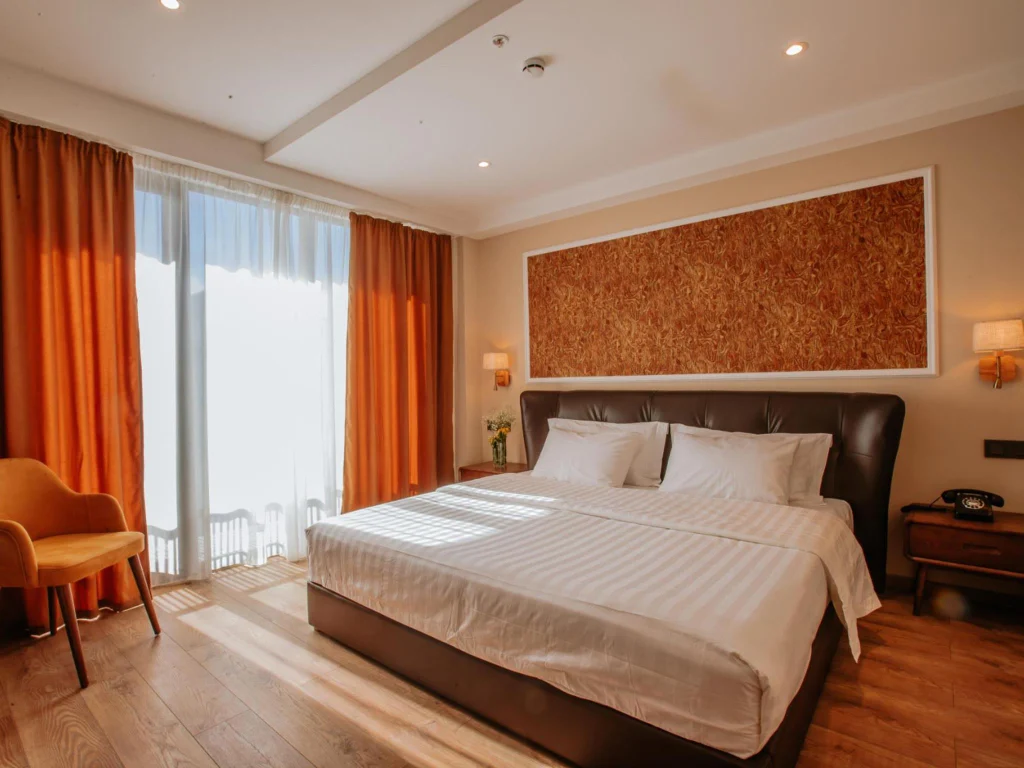 Boutique Hotel Kviria — Hotel room with a large bed, orange curtains, and balcony access.