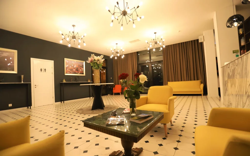 Bricks Hotel — Hotel lobby with yellow armchairs, chandeliers, and patterned tile flooring.