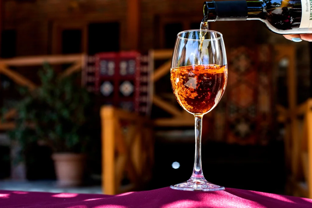 Brothers khutsishvili wine cellar — Wine being poured into a glass on a restaurant terrace table setting.
