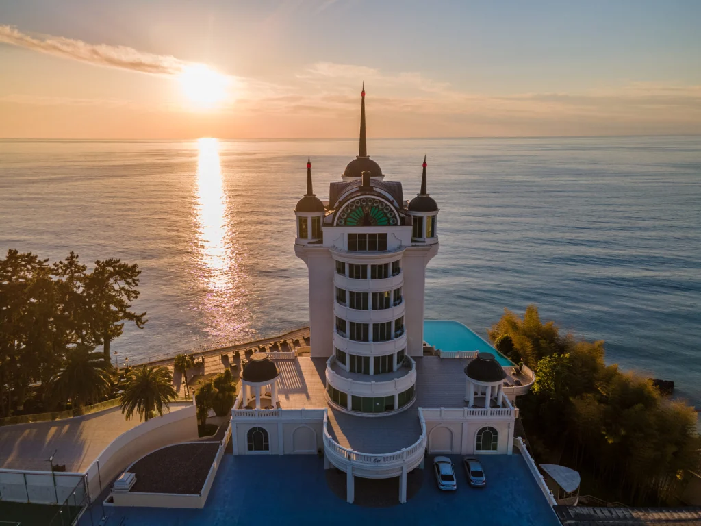 Castello Mare Hotel & Wellness Resort — Aerial view of the castle-style hotel tower beside the sea at sunset.