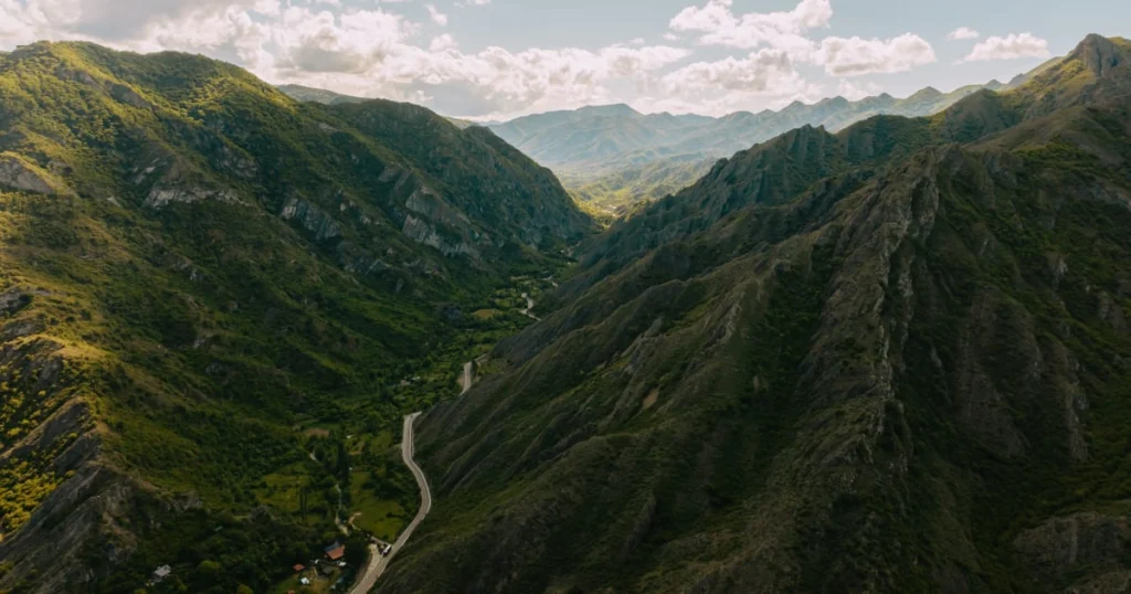 Chateau Ateni — Aerial view of a green mountain valley with a winding road near the property.