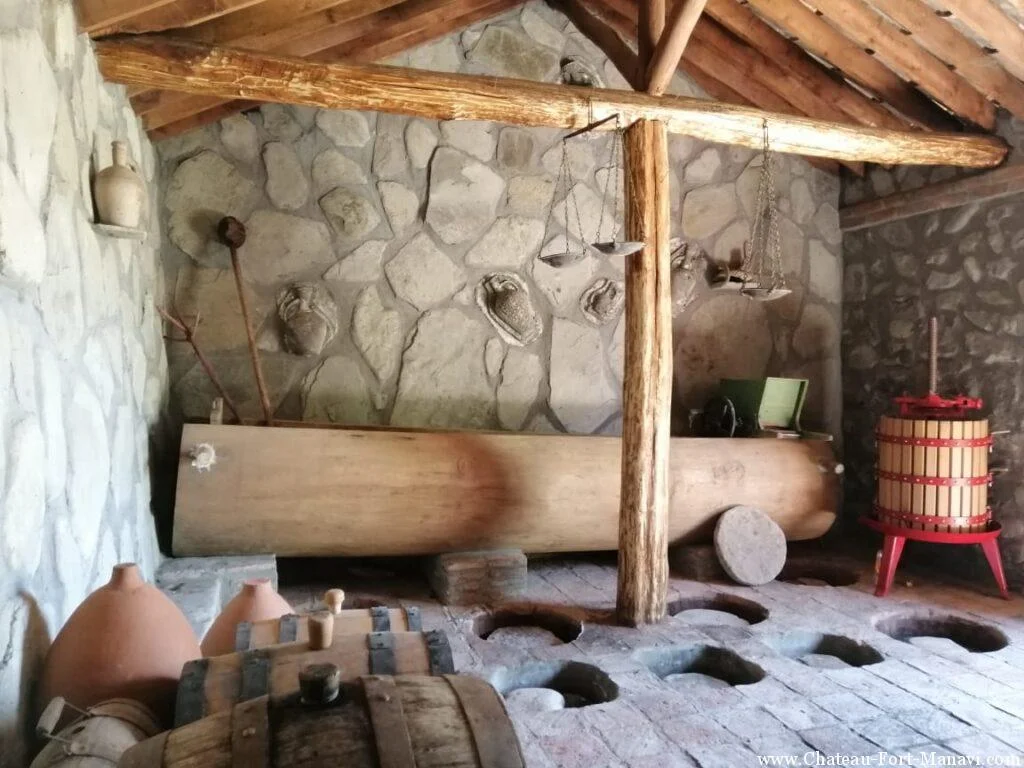 Chateau Fort de Manavi — Traditional wine cellar room with wooden press, clay jars and barrels.