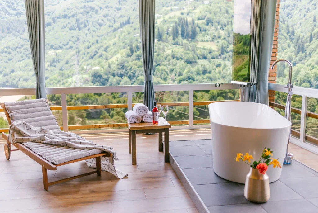 Chateau Iveri — Private balcony with soaking tub overlooking forested mountain valley.