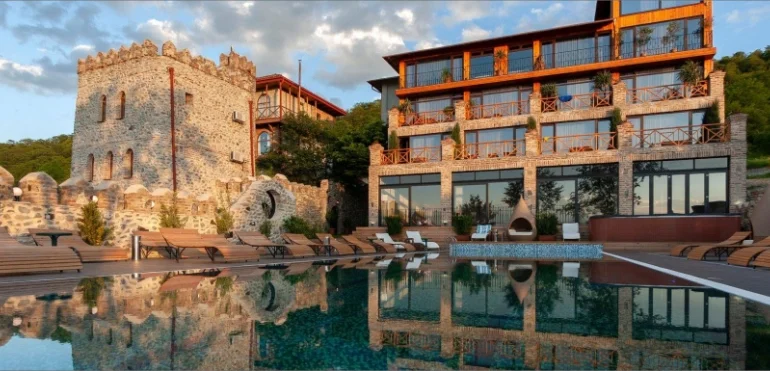 Chateau Mere — Stone castle-style building with pool and loungers at sunset.