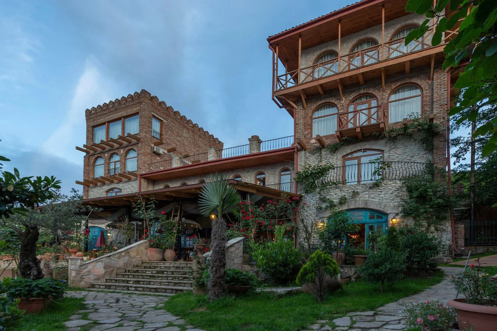 Chateau Mere — Brick and stone hotel exterior with balconies and lush garden courtyard.