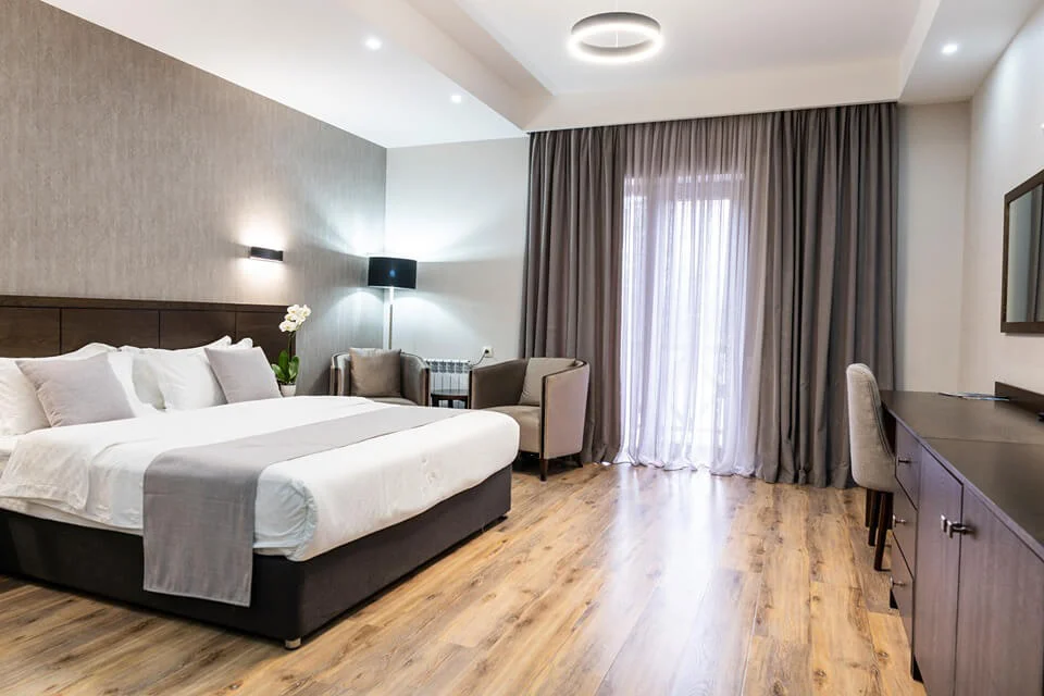 Crystal Hotel & Spa — Spacious hotel room with king bed, seating area, and large curtained window.