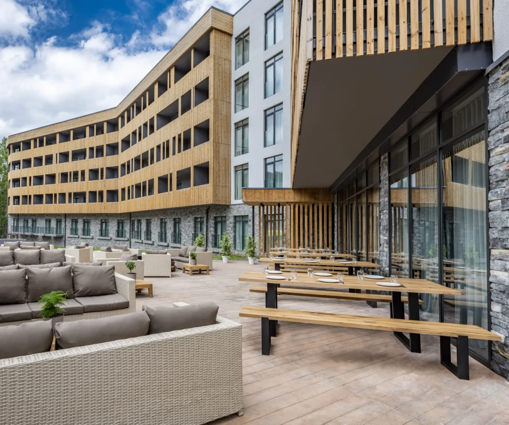 Dialog Kokhta Bakuriani — Outdoor dining terrace with wooden tables set against the hotel building.