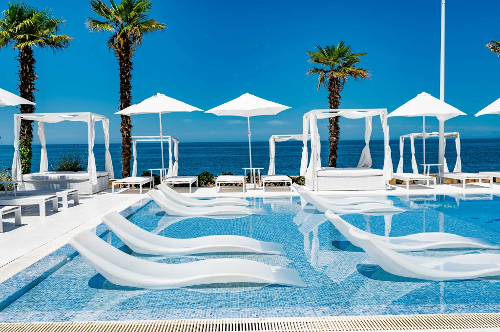 Dreamland Oasis Hotel — Upscale poolside lounge area with white daybeds and sea view.