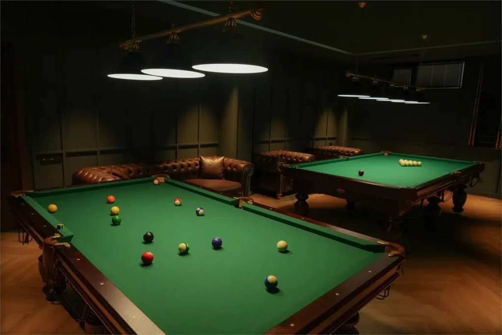 EIKON APARTMENTS — Billiard room with two pool tables, leather seating, and overhead lighting.