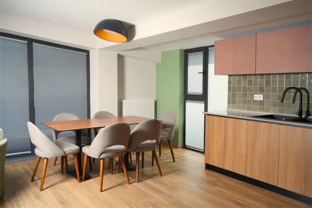 EIKON APARTMENTS — Modern apartment living area with dining table, kitchenette, and wood flooring.