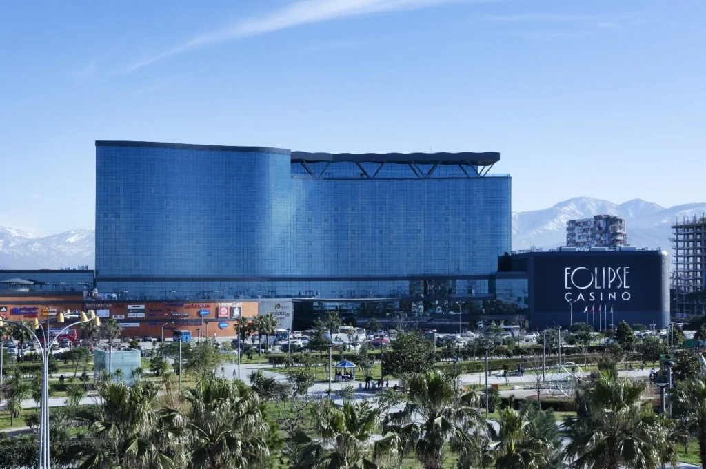 Euphoria Hotel Batumi — Large glass hotel building exterior with palm trees and mountain backdrop.