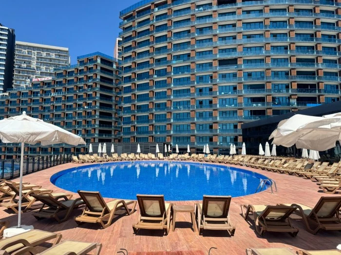 Euphoria Hotel Batumi — Outdoor round swimming pool surrounded by sun loungers and high-rise buildings.