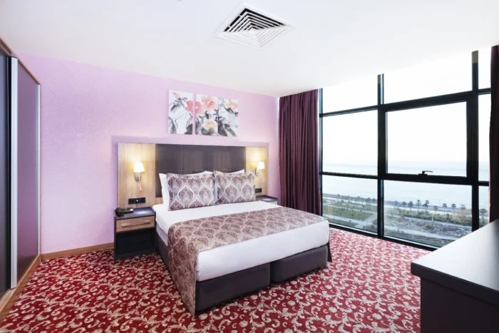 Euphoria Hotel Batumi — Hotel bedroom with large bed and floor-to-ceiling windows overlooking the sea.