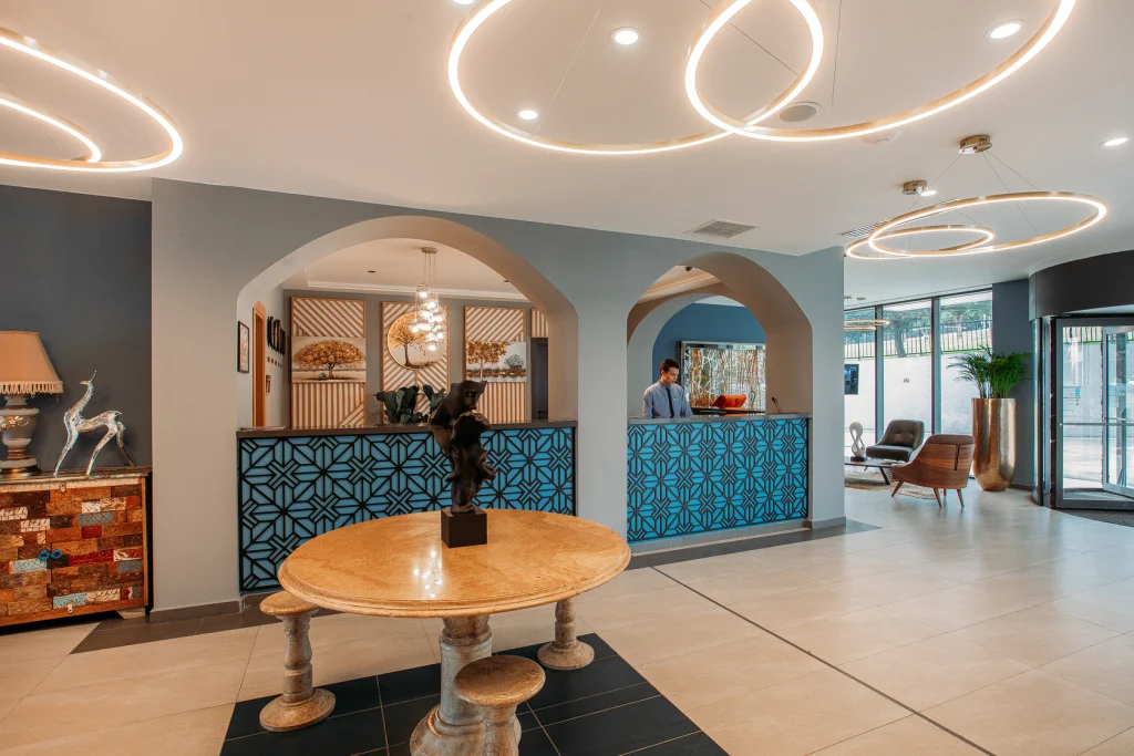 Gino Seaside Tbilisi, Trademark Collection by Wyndham — Modern hotel lobby with curved lighting fixtures, a reception desk, and seating area.