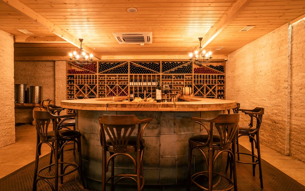 Gori Inn — Wine cellar lounge with a round bar and stocked wine racks along the walls.