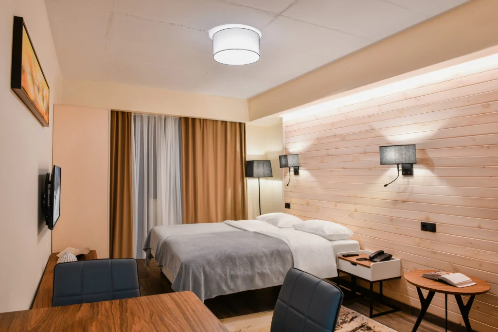Gudauri Hills Apart Hotel — Cozy hotel room with double bed, wood-paneled wall, and seating area.