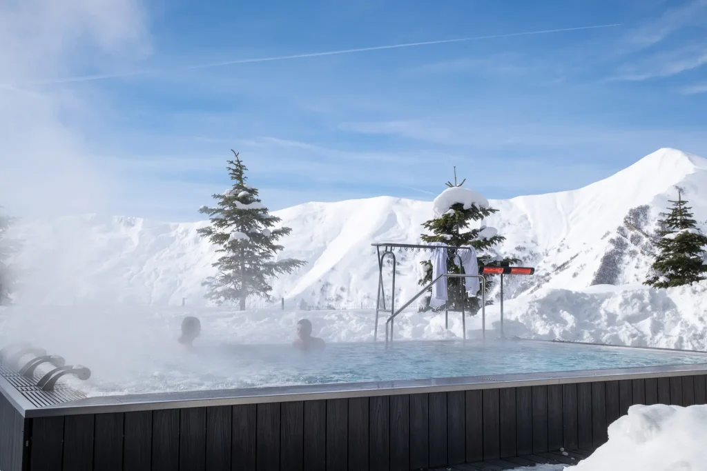 Gudauri Lodge — Outdoor heated pool with steam rising, surrounded by snowy mountain scenery.