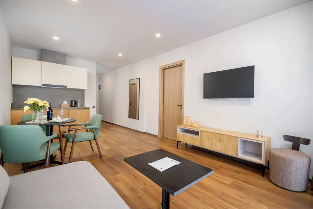 HOTEL BLUE SKY — Suite living area with kitchenette, dining table and television.