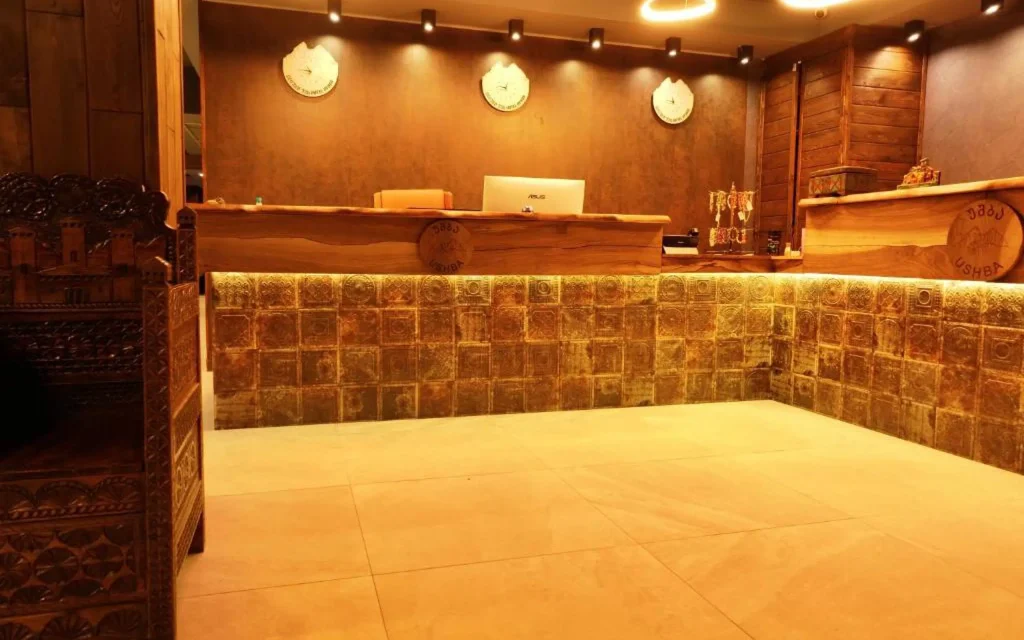 HOTEL USHBA — Hotel reception area with wooden counter and decorative tiled accents.