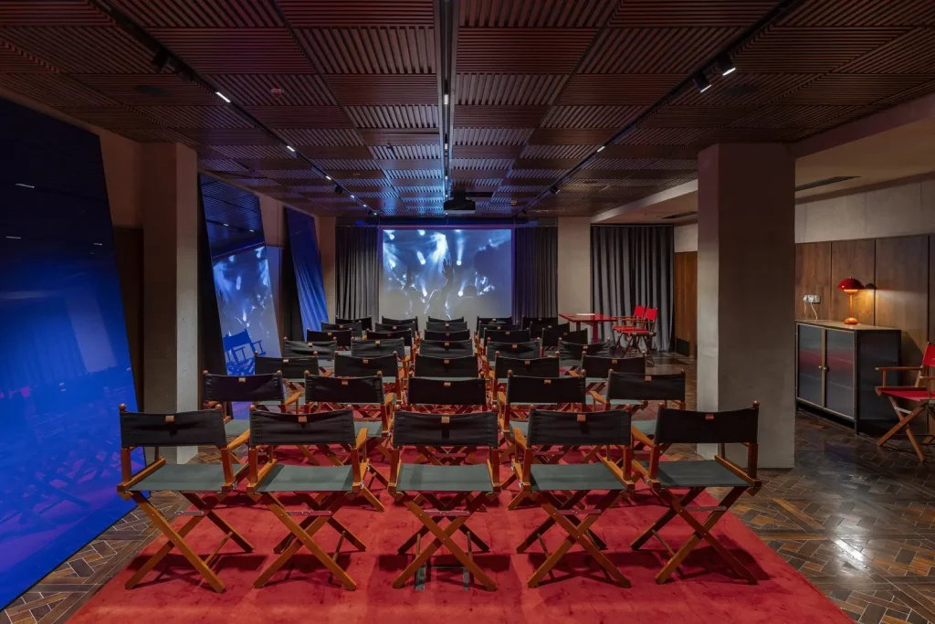 Hotel Afisha — Hotel screening room with rows of director's chairs facing a projection screen.