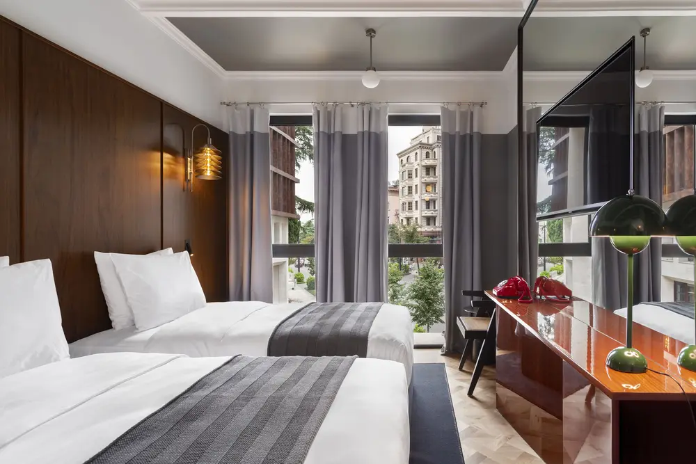 Hotel Afisha — Hotel room with twin beds, wood headboard panel, and a window view of the street.