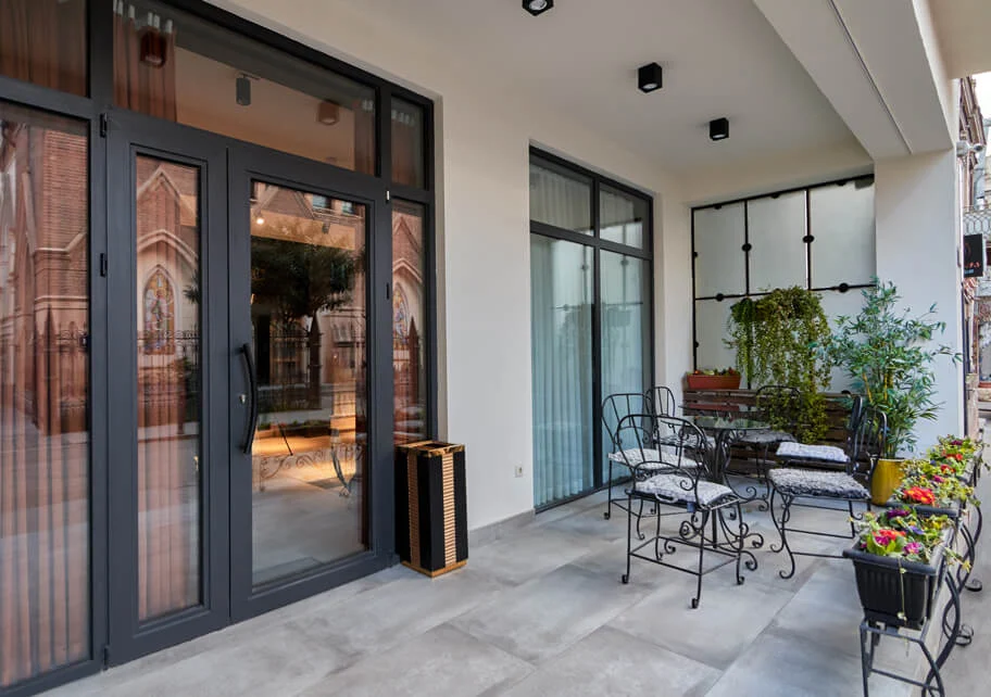 Hotel City — Outdoor terrace with seating overlooking a church facade across the street.