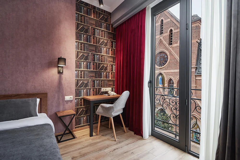 Hotel City — Guest room balcony door opens to a view of a historic church building.