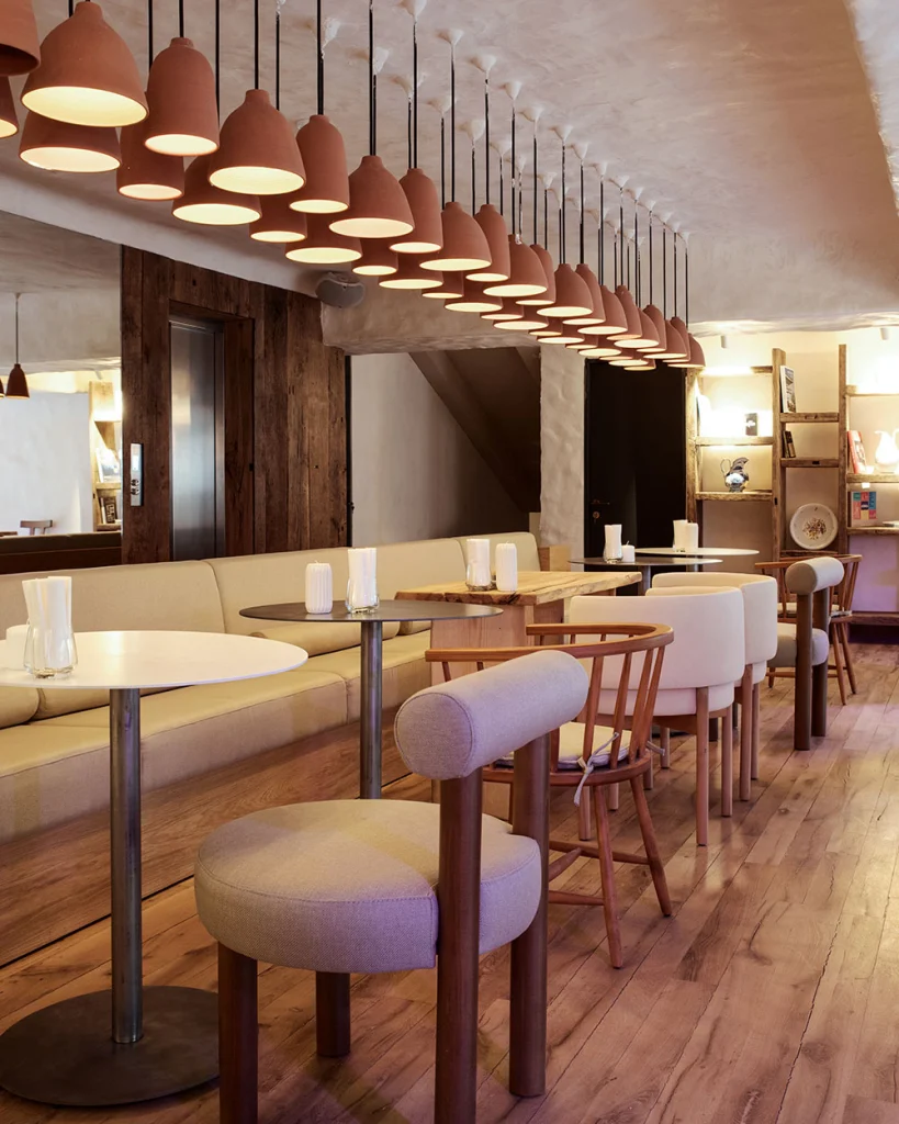 Hotel Costé — Stylish restaurant lounge with pendant lights, wooden tables, and upholstered seating.