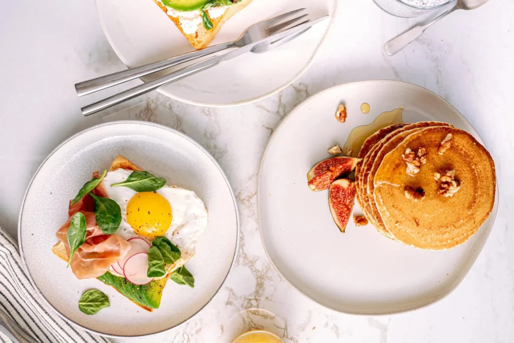 Hotel Flower — Breakfast spread with eggs, pancakes, and fresh figs served on white plates.