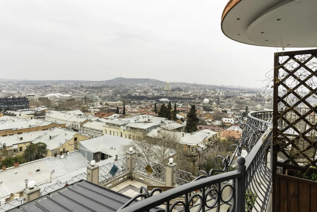 Hotel Flower — Elevated balcony view overlooking a historic city skyline with rooftops and hills.