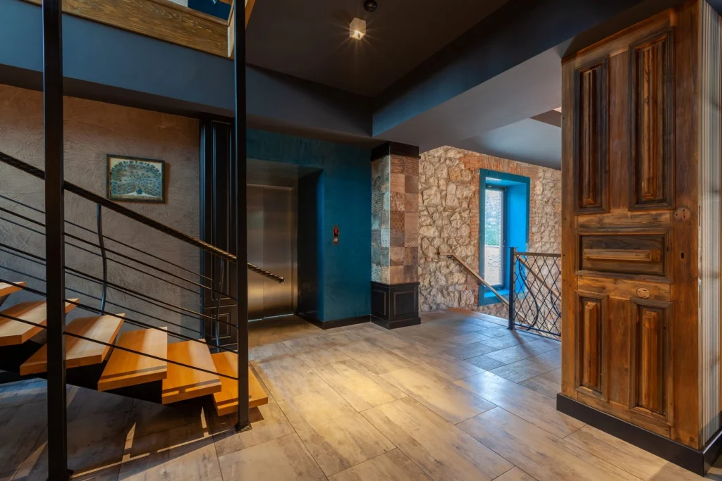 Hotel Solomon — Interior landing with elevator, wooden staircase, and stone wall details.