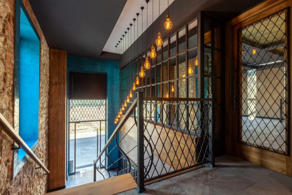 Hotel Solomon — Staircase hallway with decorative hanging lights and stone and wood accents.