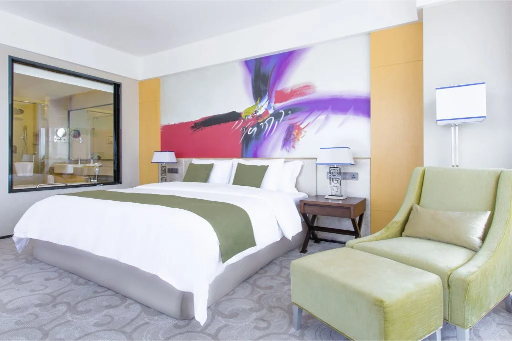 Hotels & Preference Hualing Tbilisi — Bright hotel room with a king bed, armchair, and colorful wall artwork.