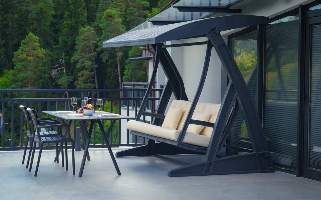 IFANI — Private balcony with dining table and swing seat overlooking a forested hillside.