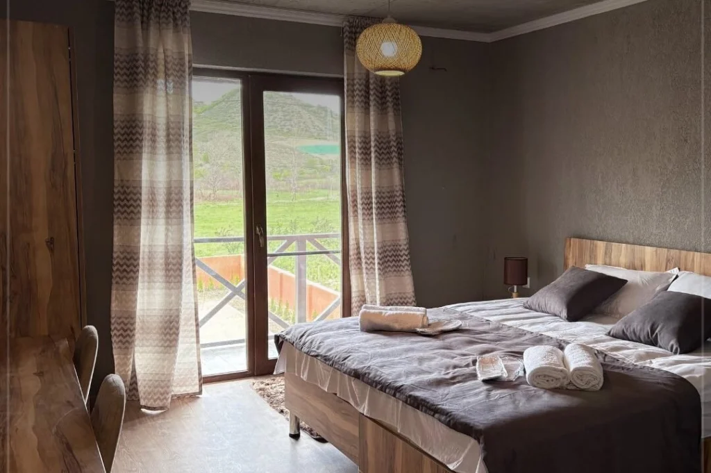 Iora Winery — Bedroom with a double bed and balcony overlooking vineyard scenery.
