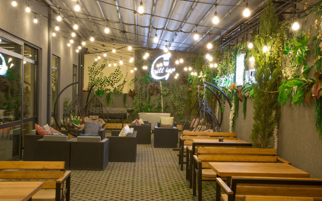 Iveria Inn — Outdoor lounge terrace with string lights, greenery, and cozy seating for guests.